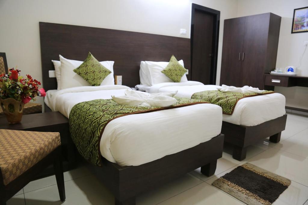 a hotel room with two beds with white sheets at Hotel Green Park Elite in Kākināda