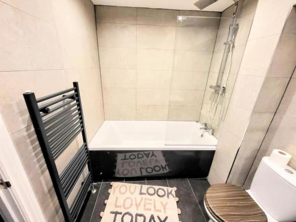a small bathroom with a tub and a toilet at Large Modern House with Private Parking in Heeley