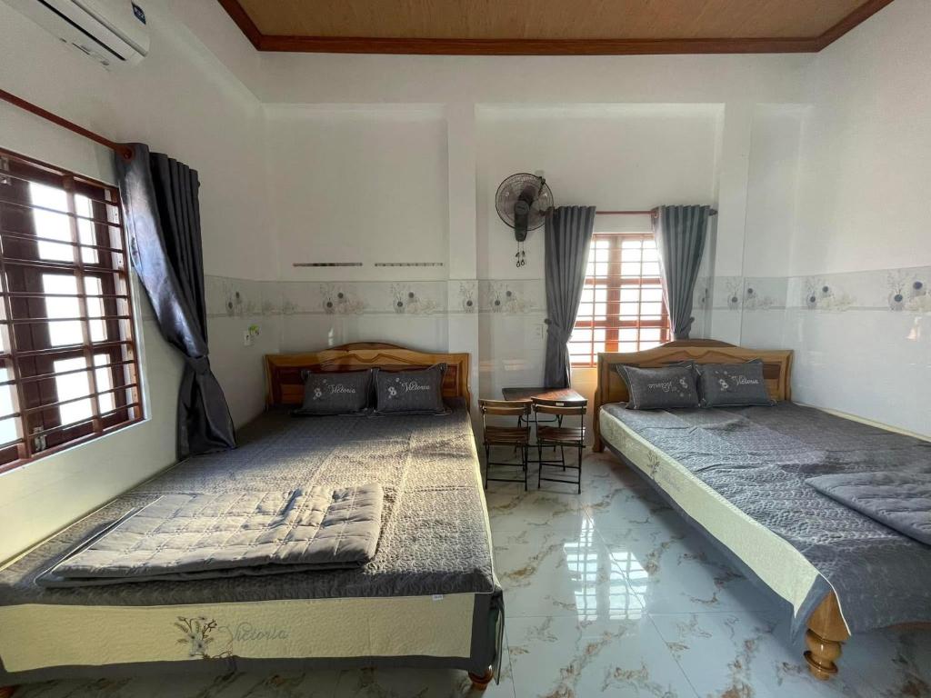 two beds in a room with two windows at Nhật Huy Homestay 