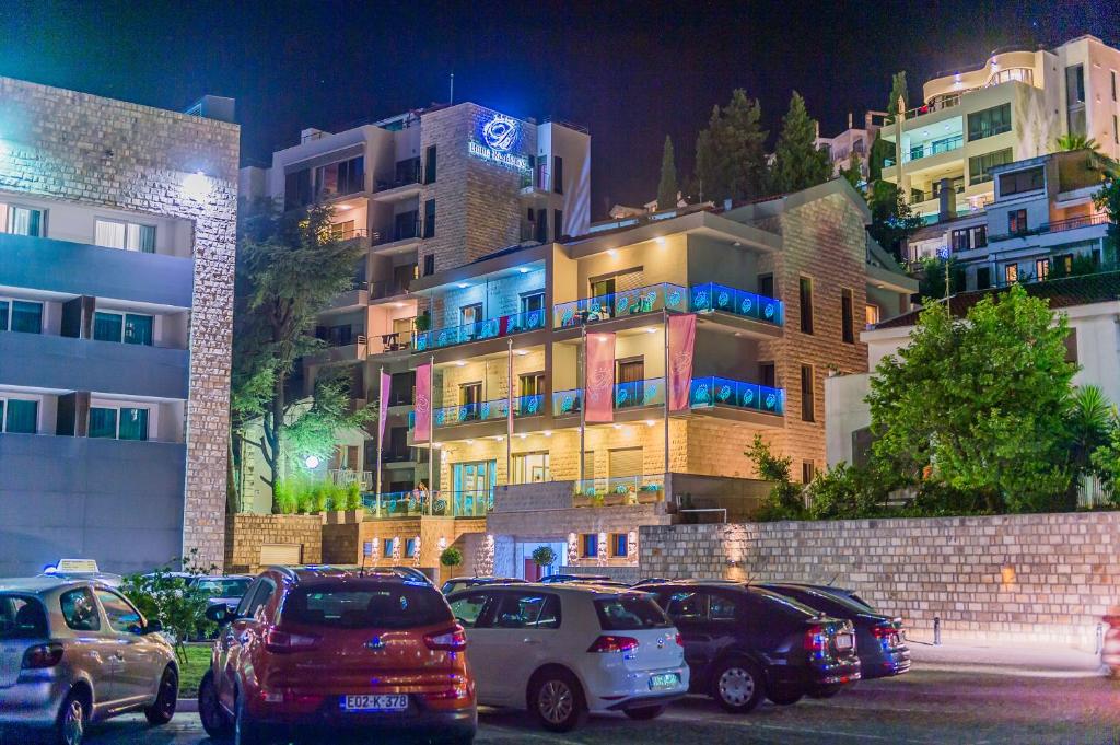 un estacionamiento con autos estacionados frente a un edificio en Hotel Butua Residence, en Budva