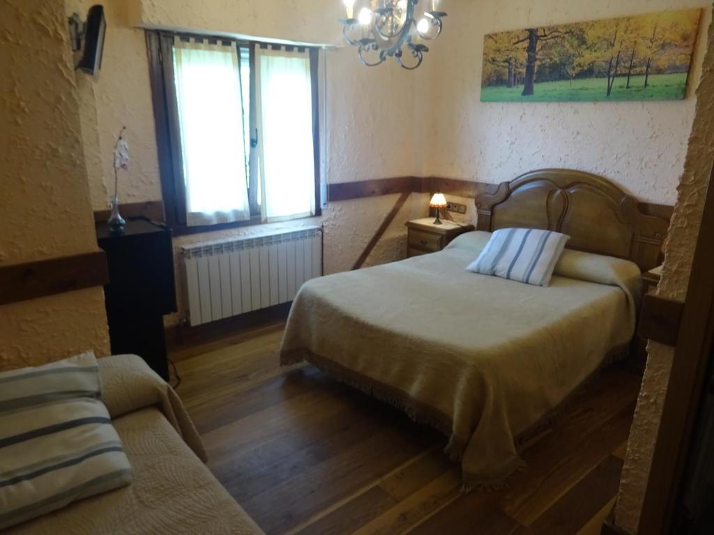 1 dormitorio con cama, sofá y ventana en Casa Rural Arratzain, en Usúrbil