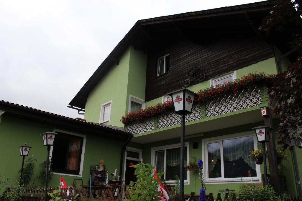 ein grünes Haus mit schwarzem Dach und Blumen darauf in der Unterkunft Gasthaus Zum Stadtwald in Rottenmann