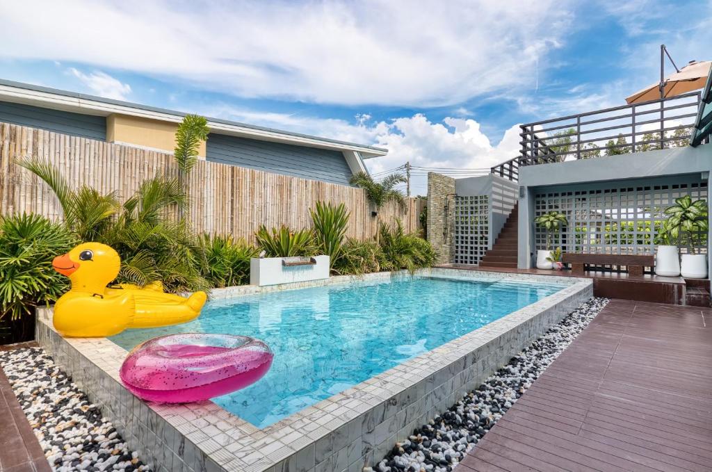 ein Swimmingpool mit einem Gummientenspielzeug neben einem Haus in der Unterkunft Thebeyonder house Pattaya, Pet friendly in Ban Huai Yai
