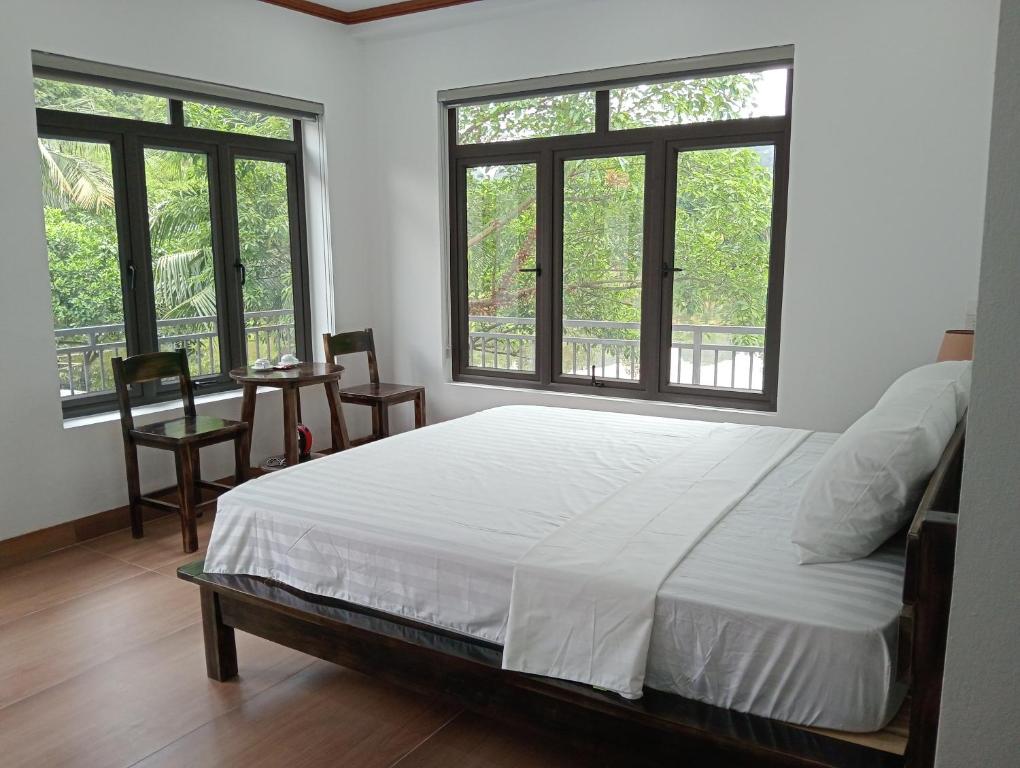 a bedroom with a bed and two windows at Tam Coc Mountain Light Homestay in Ninh Binh