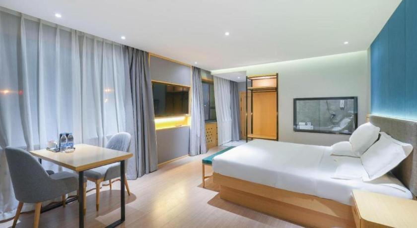 een slaapkamer met een groot bed en een tafel en stoelen bij Green Tree Inn Urumqi San'gong Metro Station Exit in Ürümqi