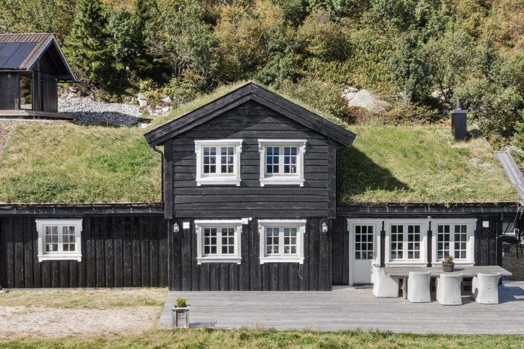 a black house with a grassy roof with white windows at Modern Family Cabin Near Vinterland Ski Resort in Lifjell