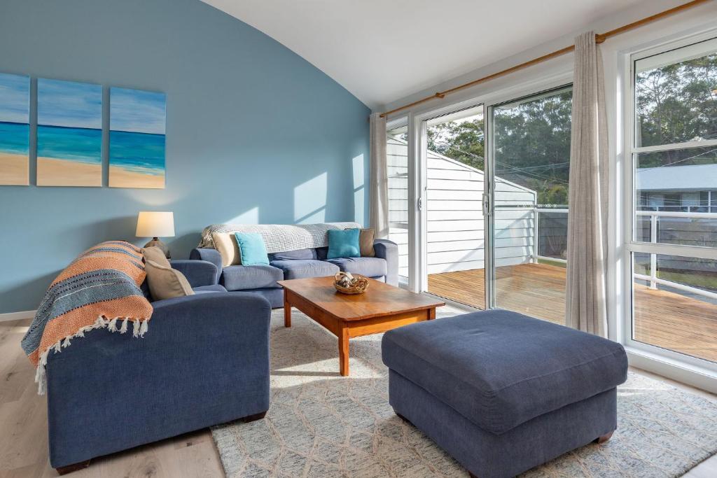 Sala de estar azul con sofá y mesa en 4 Harrow Drive, en Boomerang Beach