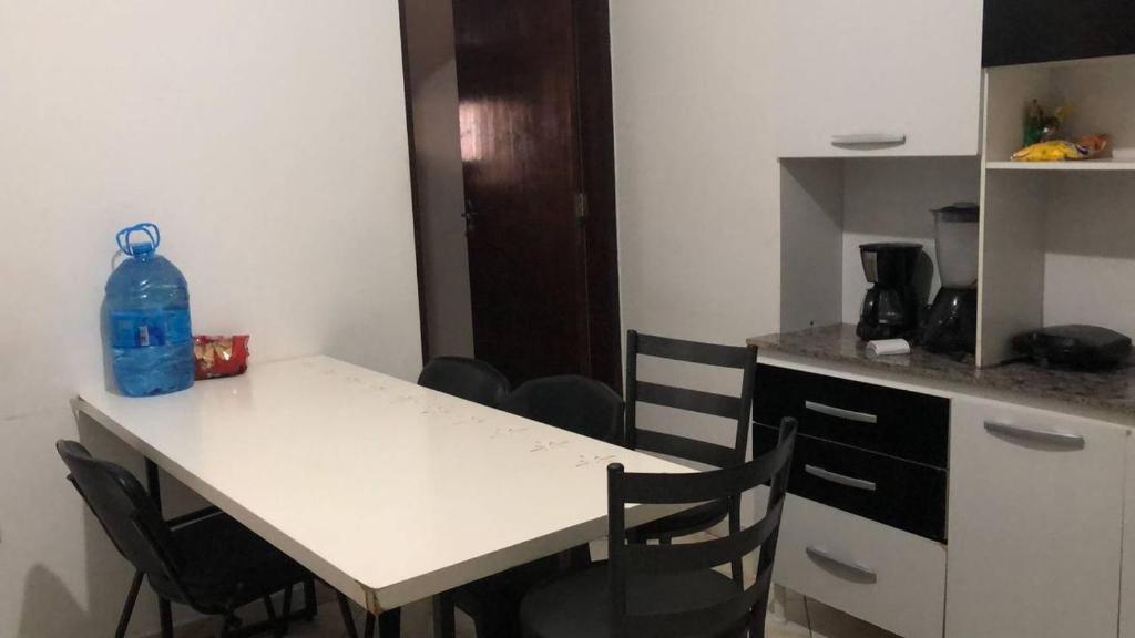 a kitchen with a table with chairs and a blue bottle on it at Hostel Pedacinho do Céu in Barueri