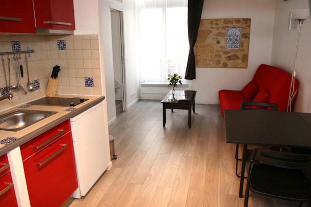 una cocina con armarios rojos y un sofá rojo en una habitación en Very heart of Paris, Charming, en París