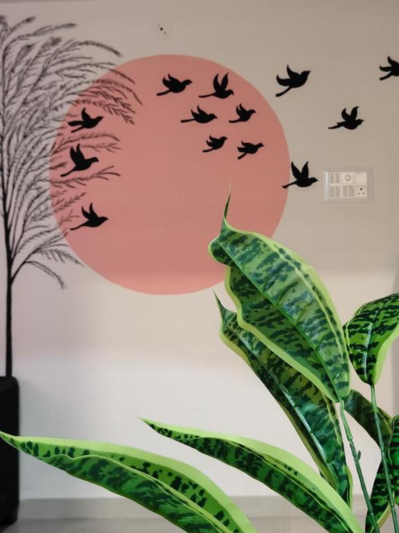 a wall with birds flying in front of a sunset at Staeg Nirvana 2BHK in Indore