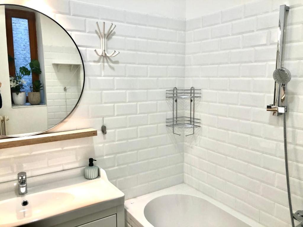 a white bathroom with a tub and a mirror at Muzeum design Apartment at downtown in Budapest