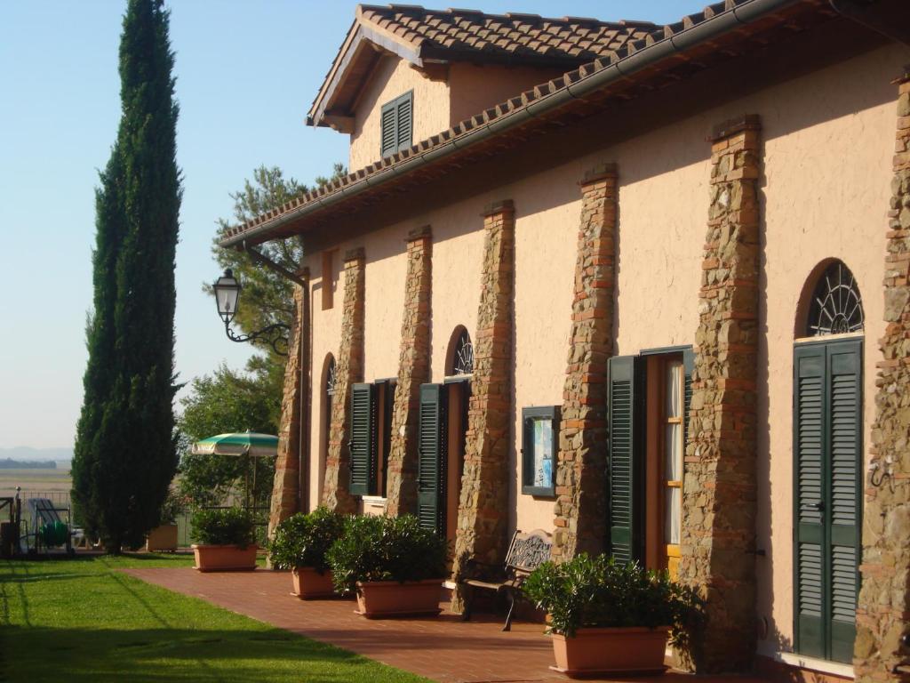 a building with green shutters and plants in a yard at Residenza Le Galere in Castiglione della Pescaia