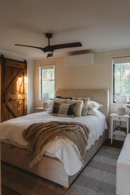 a bedroom with a large bed and a ceiling fan at Sugarloaf - Luxury Farmhouse Cabin in Bunburra