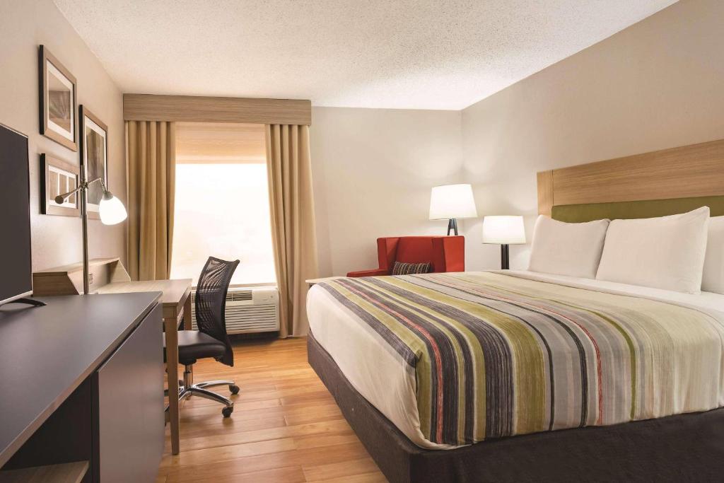 a hotel room with a bed and a desk at Country Inn & Suites by Radisson, North Little Rock, AR in North Little Rock