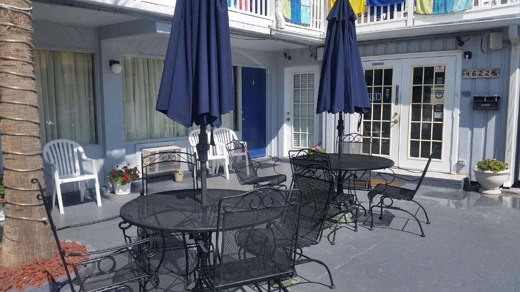 2 Tische und Stühle mit Sonnenschirmen auf einer Terrasse in der Unterkunft Edgewater Inn in Myrtle Beach