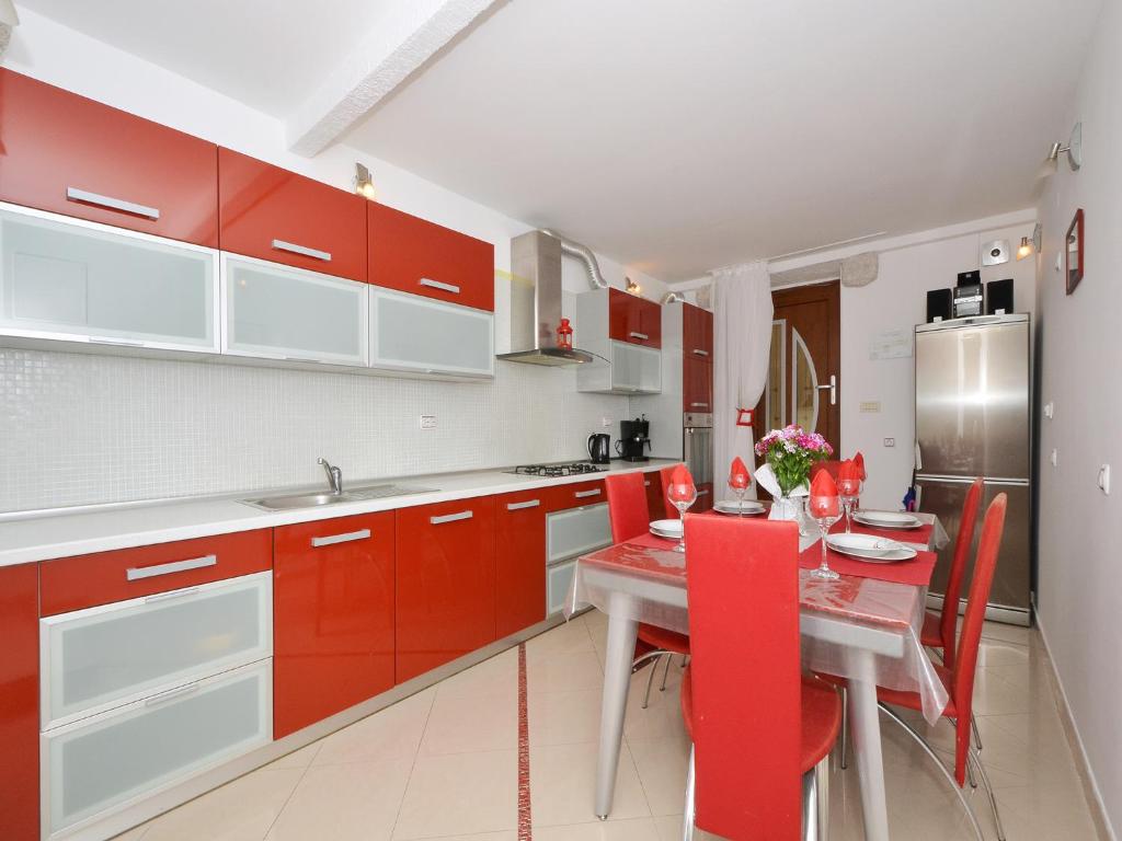 a kitchen with red cabinets and a table with red chairs at Apartment Nikolina in Trogir