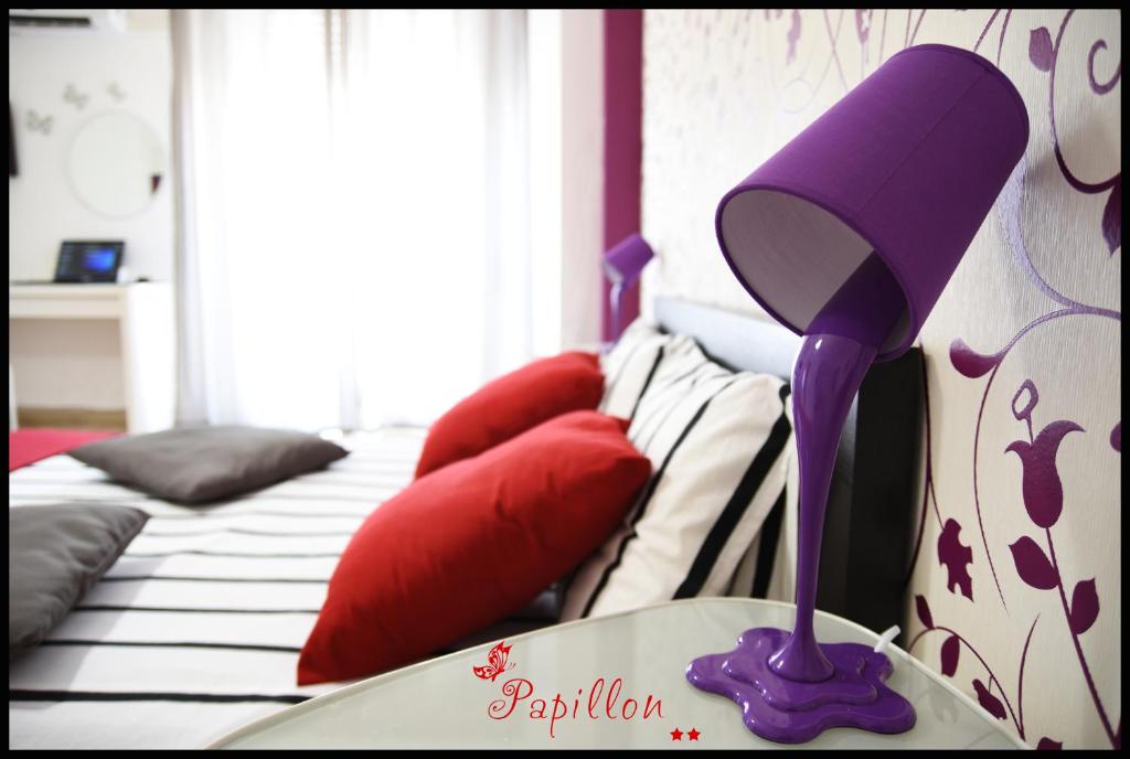 a bedroom with a bed with a purple lamp on it at Papillon BnB in Palermo