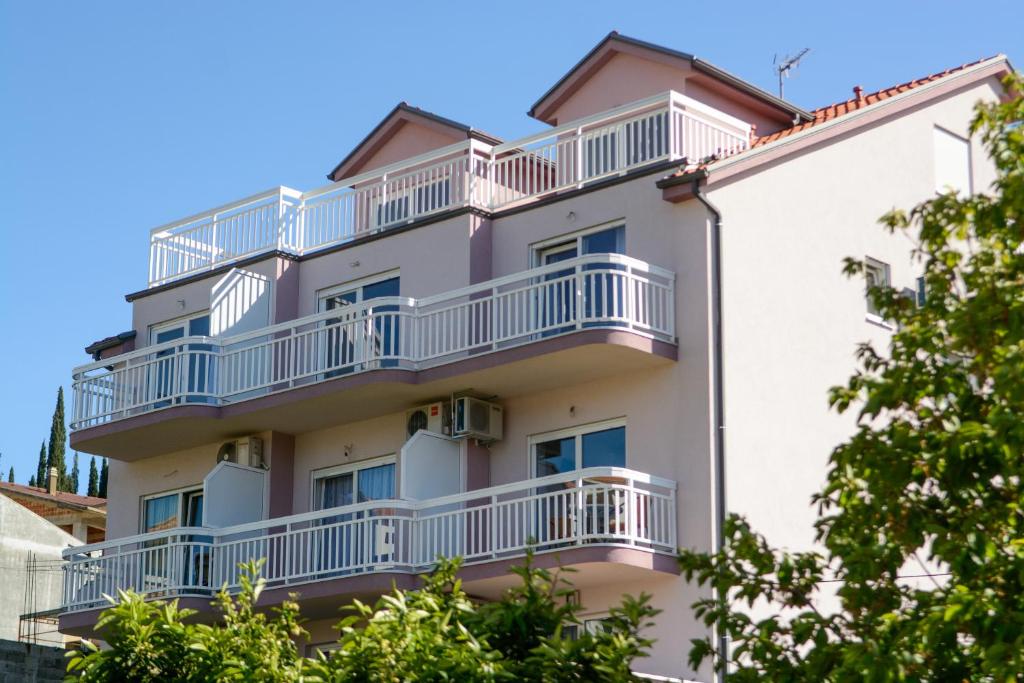 an apartment building with white balconies and trees at Apartmani MM in Trogir