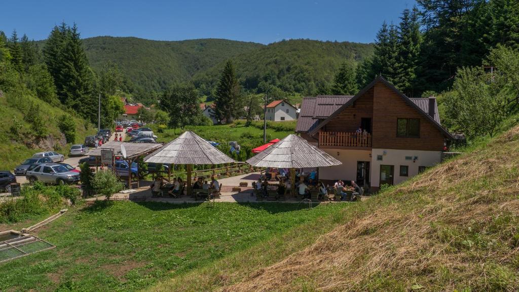 eine Gruppe von Menschen, die unter Sonnenschirmen in der Nähe eines Gebäudes sitzen in der Unterkunft Motel Luka in Deževice