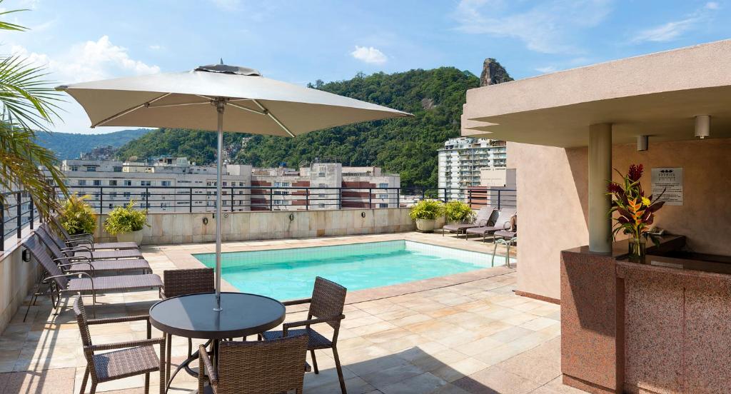 a patio with a table and umbrella and a pool at Premier Copacabana Hotel in Rio de Janeiro