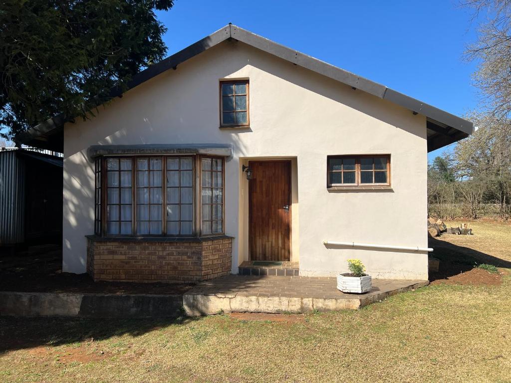 una piccola casa bianca con una porta marrone di Pavlovna Cozy 2 Cottage a Himeville