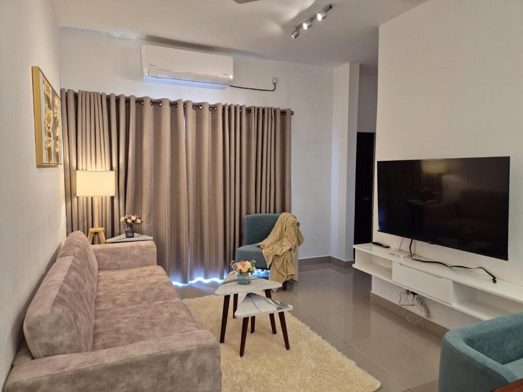 a living room with a couch and a flat screen tv at Elysian Blue Suites - Santorini Resort Negombo in Negombo