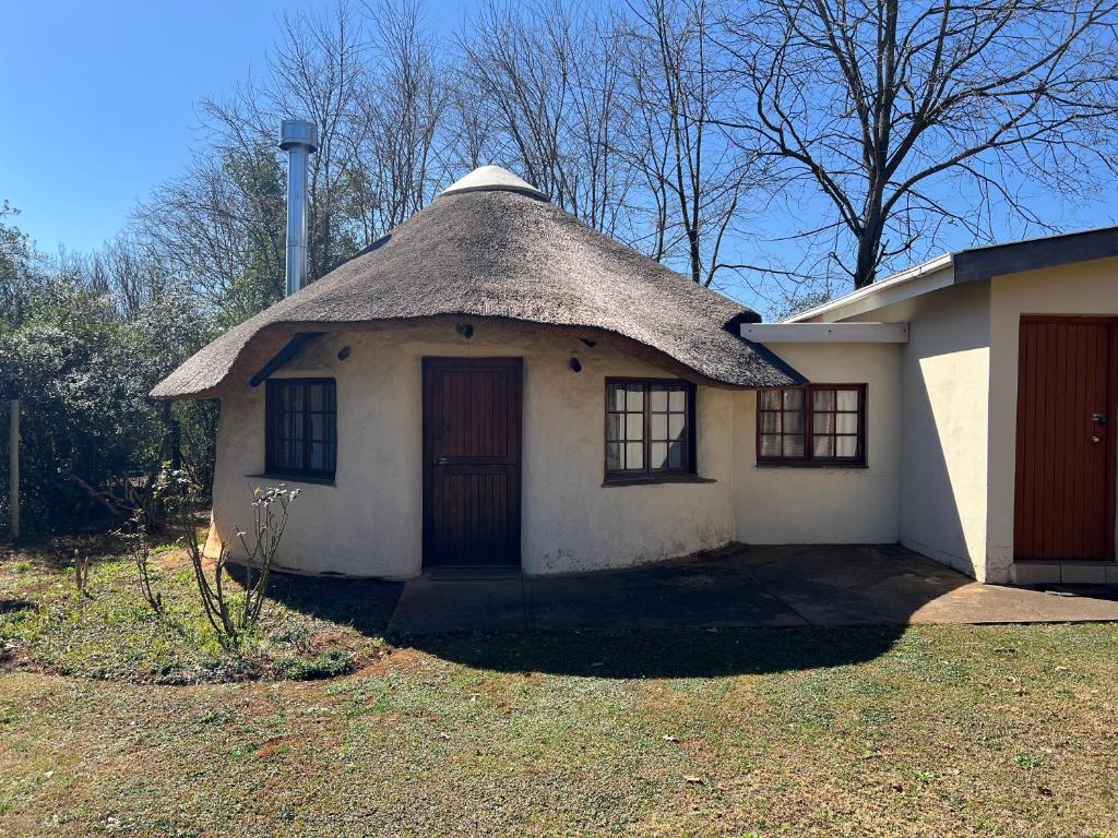 a small white house with a thatched roof at Pavlovna Bunk with the kids Cottage in Himeville