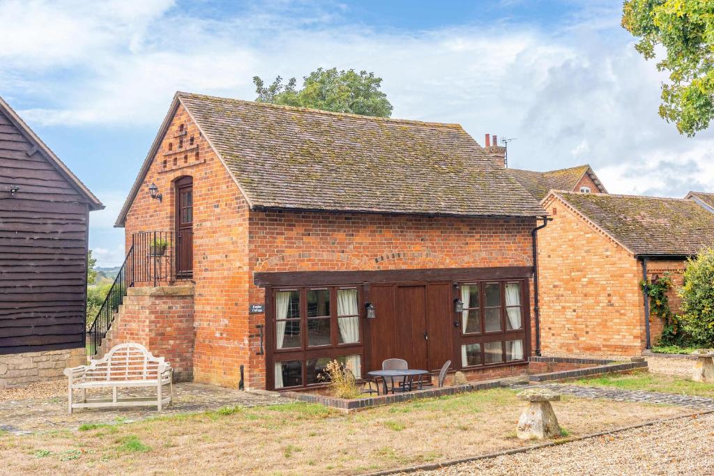 an old brick house with a bench in the yard at Poplar Cottage - Historic Barn in Dumbleton in Dumbleton