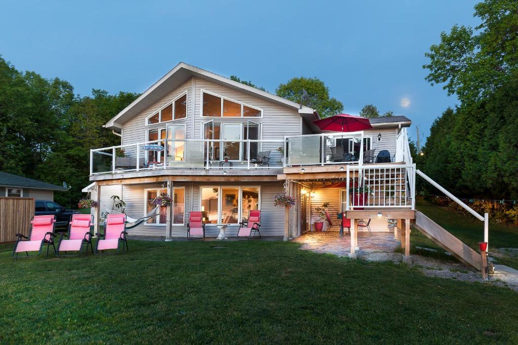 una casa con sillas rosas en el césped en N' This on the Bay -Lower Level Vacation Suite, en Wiarton
