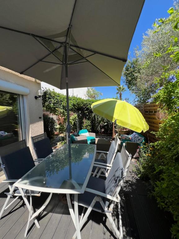 a table and chairs with an umbrella on a deck at Bel appartement T2 avec jardin indépendant in Pérols