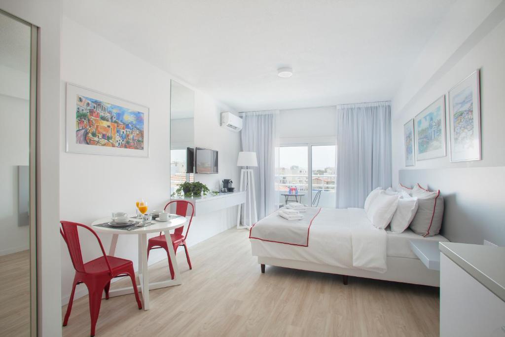 a white room with a bed and a table and chairs at Kitieos Apartments in Larnaca