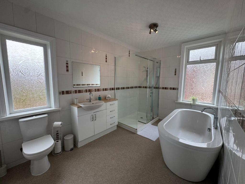 a bathroom with a tub and a toilet and a sink at The Links House Lytham St Annes in Lytham St Annes