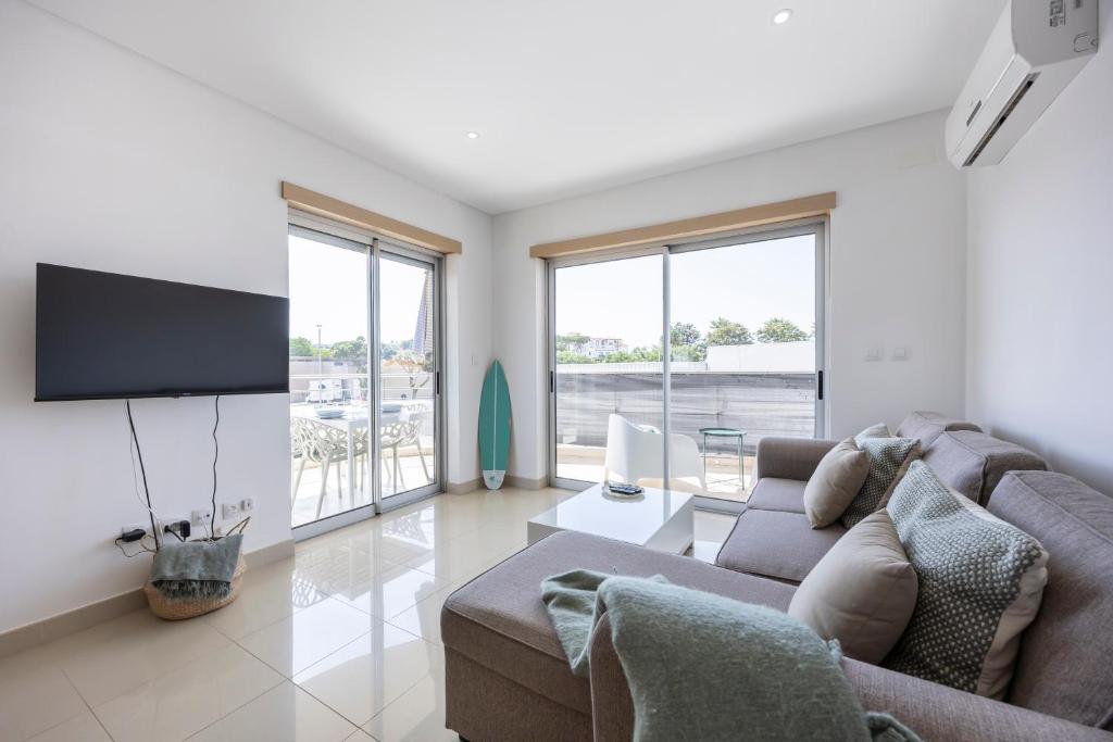 a living room with a couch and a flat screen tv at Casa A in Olhos de Água