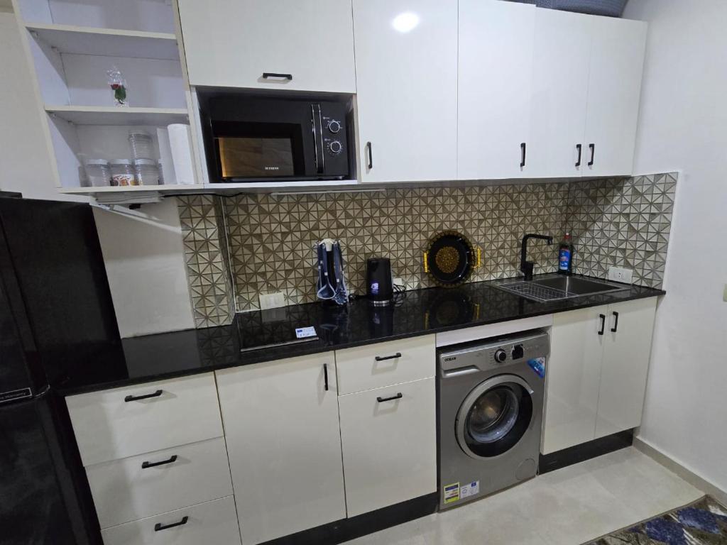 a kitchen with a washing machine and a microwave at Golden Tiba in Hurghada