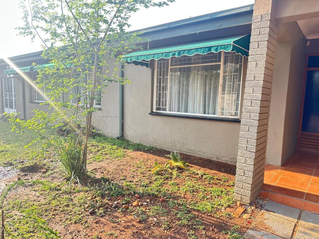 a house with a tree in front of it at MBT Lodge in Polokwane