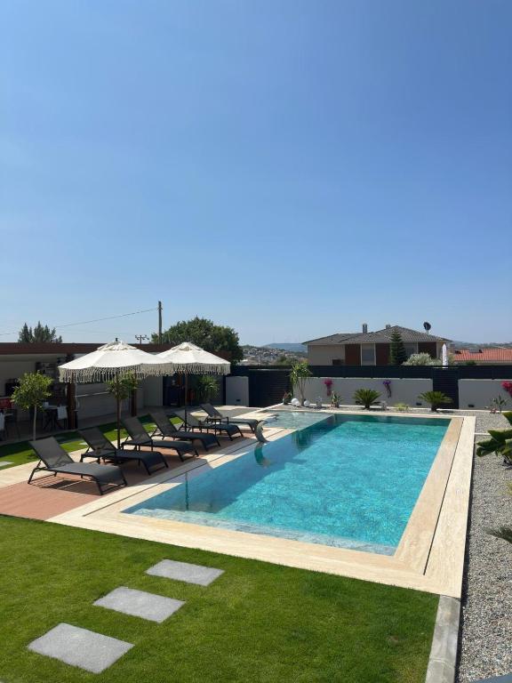a swimming pool with chairs and umbrellas on a building at Çeşme Güzel Life in Çeşme