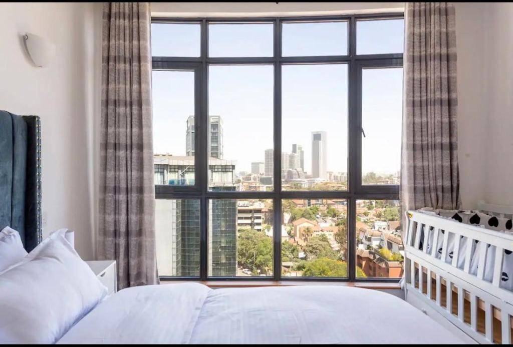 a bedroom with a bed and a large window at Skyline Aramis Apartment Westlands,2bedroom,2baths in Nairobi