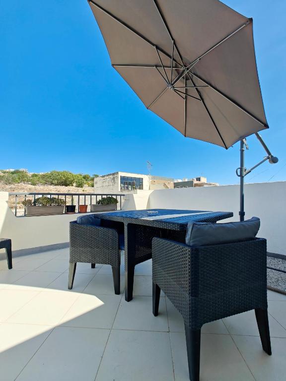 a table and chairs with an umbrella on a roof at Corner view 4 in Marsaskala