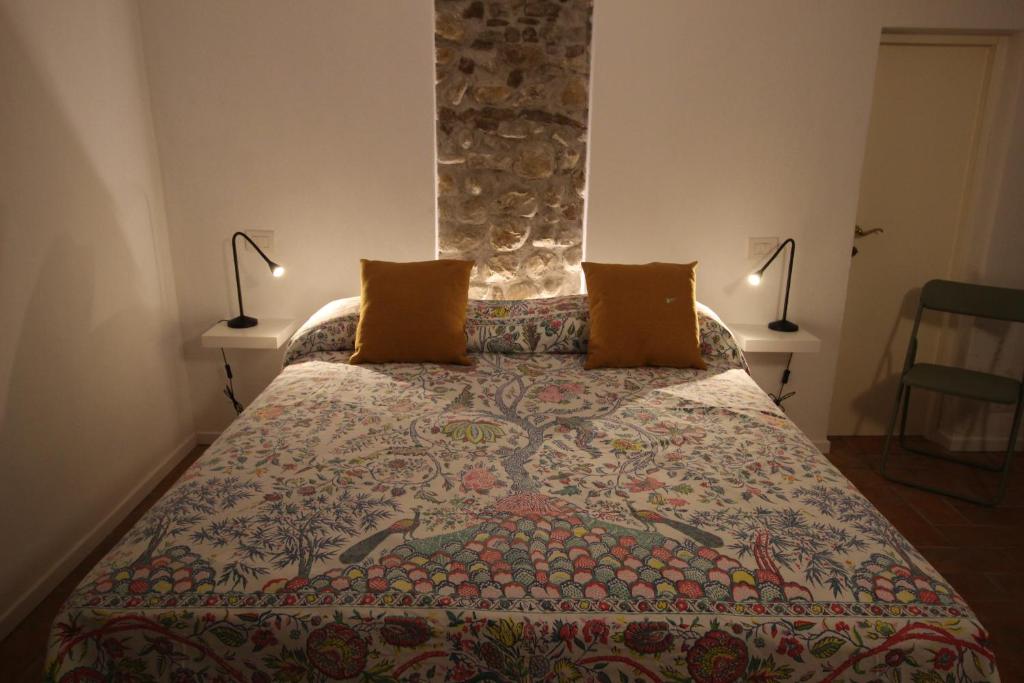 a bedroom with a bed with a colorful bedspread and two lamps at La Casetta Sulle Mura in Santarcangelo di Romagna