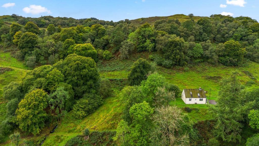 an aerial view of a house on a hill with trees at Charming 2-Bed Cottage on Tranquil Raera Farm in Kilninver