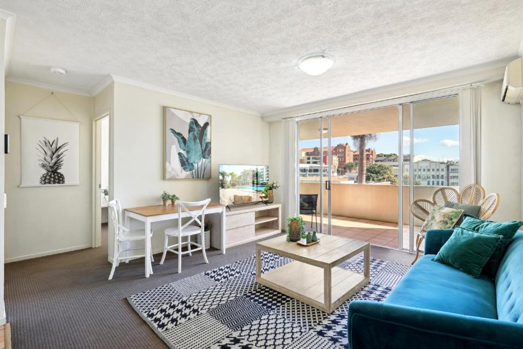 Una sala de estar con un sofá azul y una mesa. en Inner-City 1-Bed with Pool & Spa, en Brisbane
