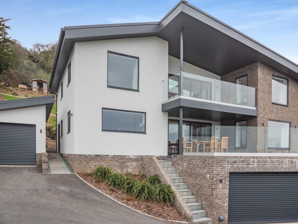 a white house with a black roof at Bodwennol - a stunning house! in Aberdyfi