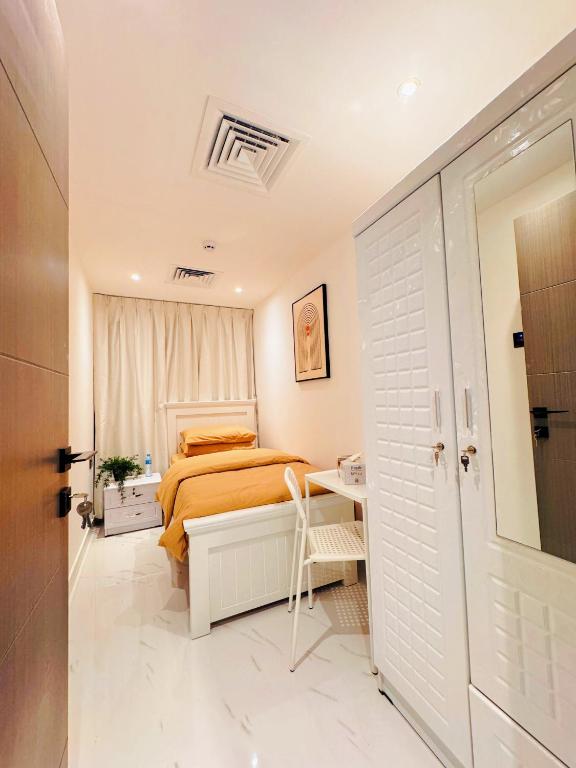 a bedroom with a bed and a table and a chair at Vogue Inn Abu Dhabi in Abu Dhabi