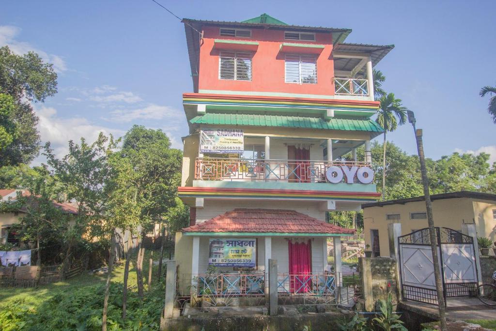 a tall orange building with a balcony at Hotel O Sandhana Homestay in Alīpur Duār