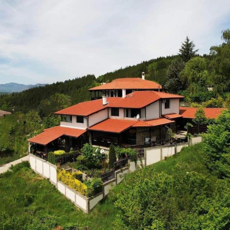 a large house with red roofs on a hill at Penev guest house in Glavatartsi