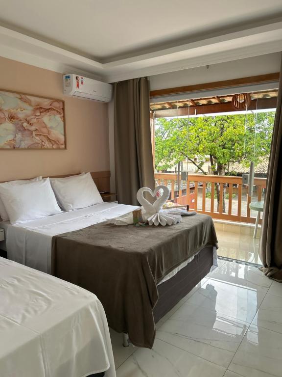a hotel room with two beds and a window at Residencial Angelina in Praia do Forte