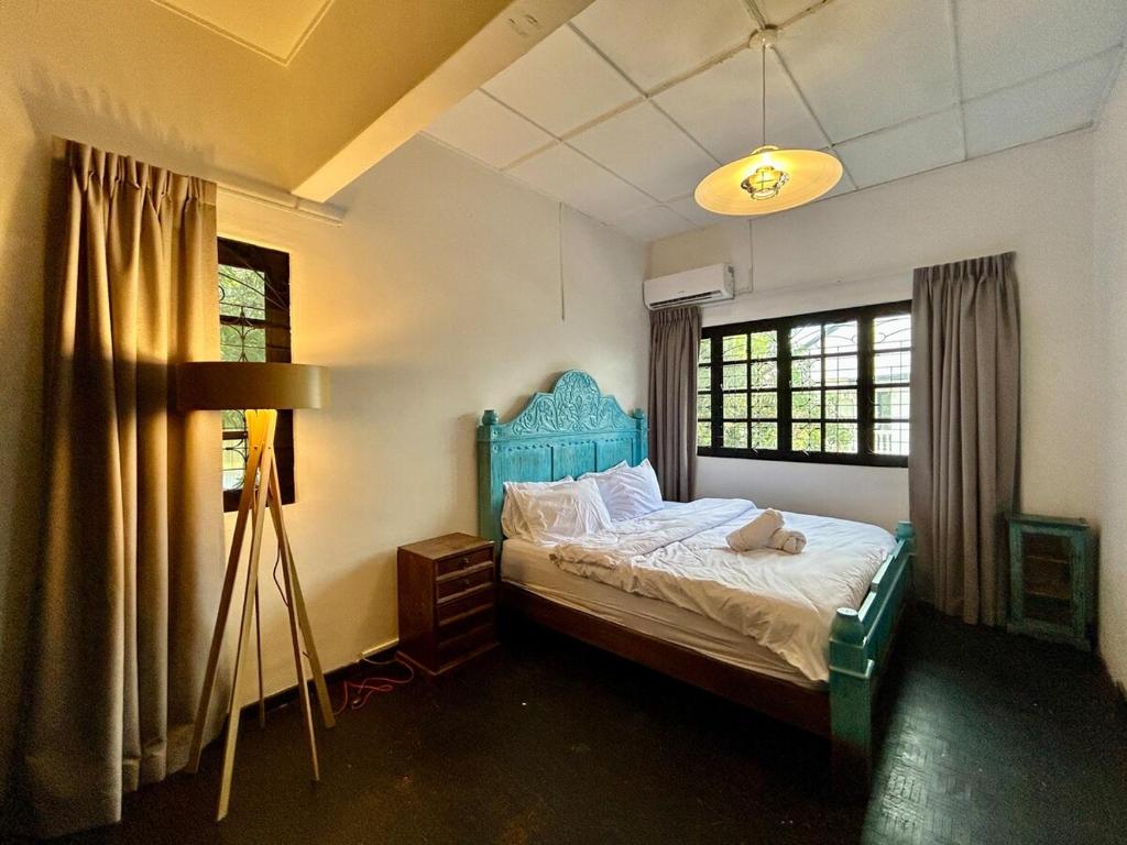 una camera da letto con un letto con testiera blu e finestre di Cozy 2BR Family Homestay in Shared Bungalow SS2 Petaling Jaya a Petaling Jaya