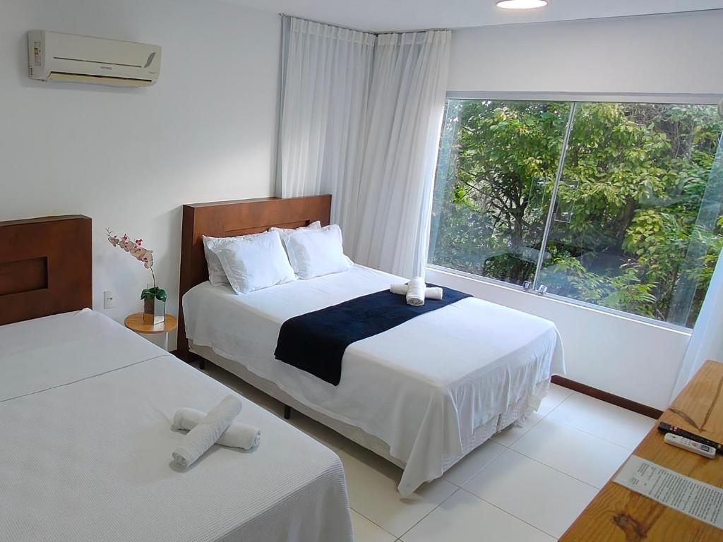 a hotel room with two beds and a window at apartamento superior quarto&sala in Maceió