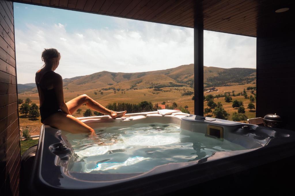 a woman sitting in a jacuzzi tub with a view at The Nook Zlatibor in Zlatibor