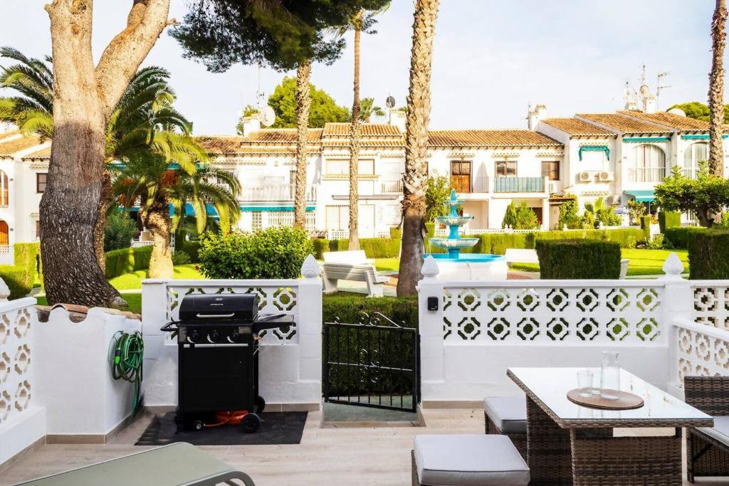 a barbecue grill on a patio with palm trees at Bungalow Pink summertime in Alicante